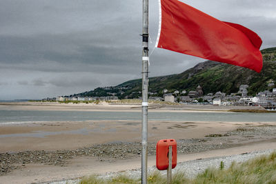 Red flag on beach against sky