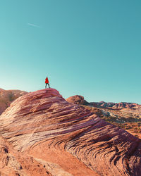 Rear view of man standing on mountain against clear blue sky
