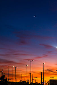 Silhouette street lights against sky at night