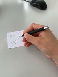 Cropped hand of man writing in paper on table