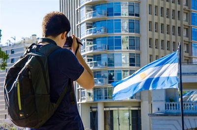 Rear view of people standing by buildings in city