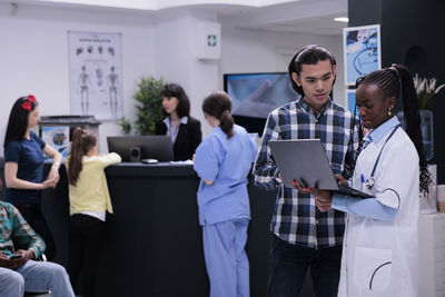 Doctor holding laptop talking with patient at hospital