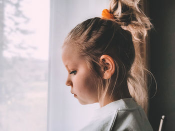 Side view of girl looking through window