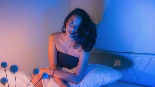 Portrait of smiling young woman sitting on bed