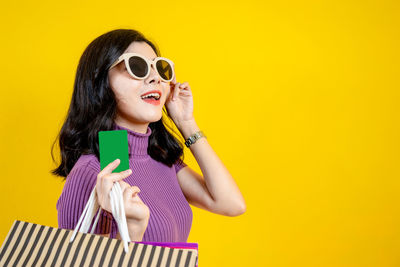 Portrait of a smiling young woman against yellow background