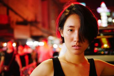 Close-up portrait of young woman in city at night