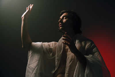 Man looking away while standing against black background