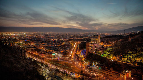 High angle view of illuminated cityscape against sky at sunset