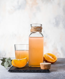 Orange lemonade in glass and bottle with fresh orange. refreshing summer drink