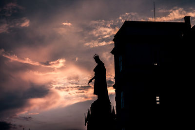 Low angle view of silhouette statue by building against sky during sunset