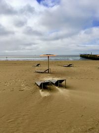 Orange parasol on empty beach in the rain