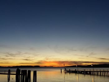 Silhouette pier over sea against sky during sunset