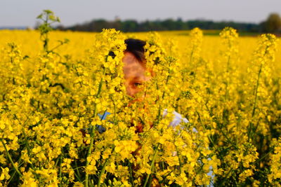 Woman standing amidst yellow flowers at oilseed rape field