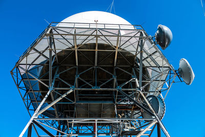 Low angle view of electricity pylon against clear blue sky