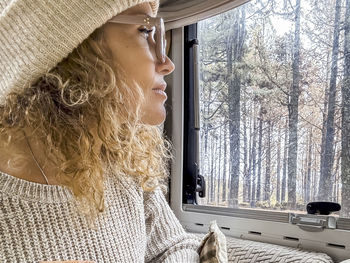Side view of woman looking through window