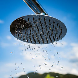 Close-up of water drops on metal against blue sky