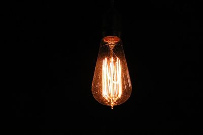 Close-up of illuminated light bulb against black background