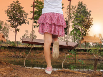 Low section of woman standing by tree against plants