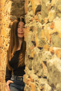Portrait of smiling young woman standing against wall