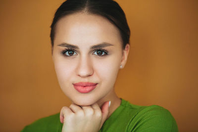 Close-up portrait of young woman against gray background