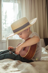 Man playing guitar while lying on bed at home