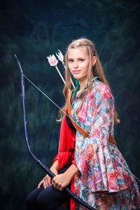 Portrait of smiling teenage girl holding bow and arrow