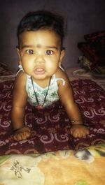 Portrait of cute girl sitting on bed at home