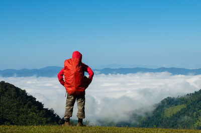 Rear view of man standing on field against mountains