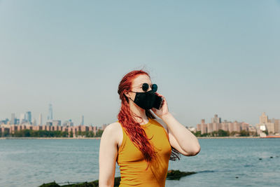 Woman standing by sea against clear sky