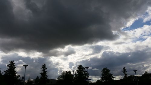 Low angle view of silhouette trees against cloudy sky
