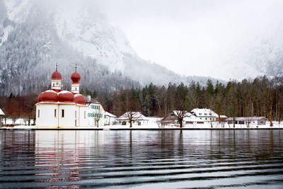 Building by lake against sky during winter