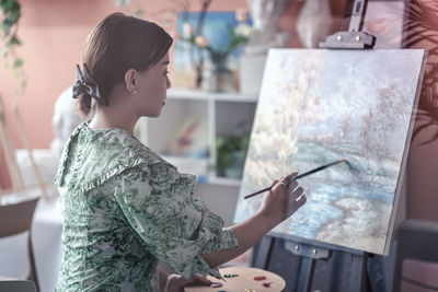 Beautiful woman painting at home