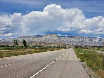 Road leading towards mountains against sky