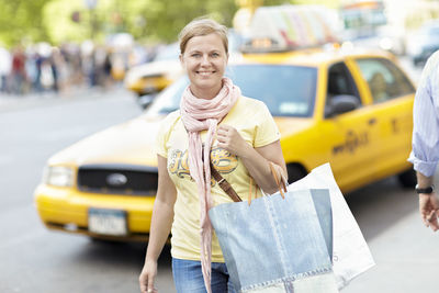 Smiling woman with shopping bag on street