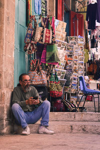 Full length of man sitting on staircase at market