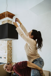 Happy couple fixing lighting equipment while renovating home