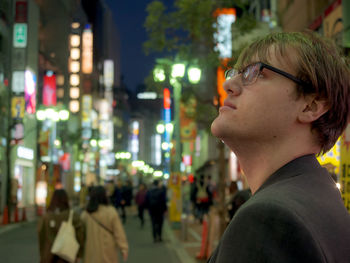 Portrait of man looking at illuminated city at night