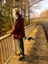 Side view of man with dog standing on sidewalk