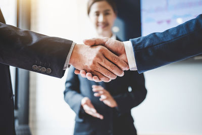 Close-up of business partners shaking hands in office