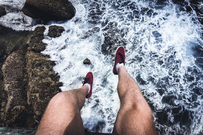 Low section of man surfing in sea