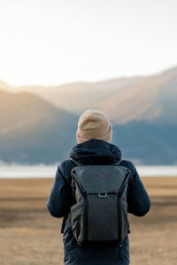 Rear view of person looking at mountain against sky