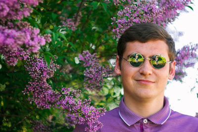 Portrait of young woman wearing sunglasses against trees