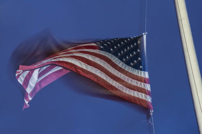 Low angle view of flag against blue sky