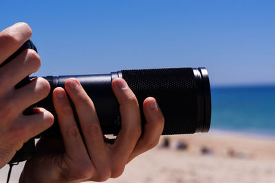 Close-up of hand holding mobile phone against sky