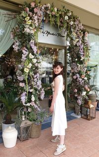 Portrait of smiling woman standing by flowering plants