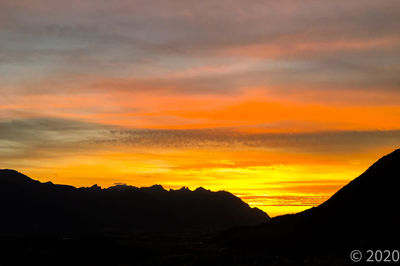 Scenic view of silhouette mountains against orange sky