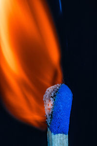 Close-up of burning candle against black background