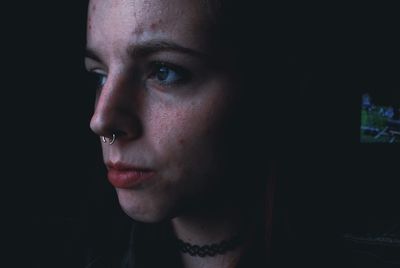 Close-up portrait of young woman over black background