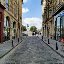 People walking on footpath amidst buildings in city