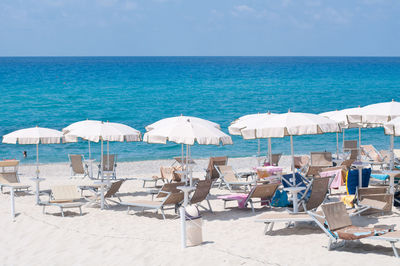 Chairs on beach by sea against sky